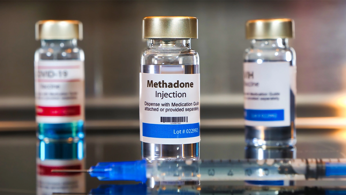 Vials of Methadone Injection and other medications, with a syringe in the foreground.