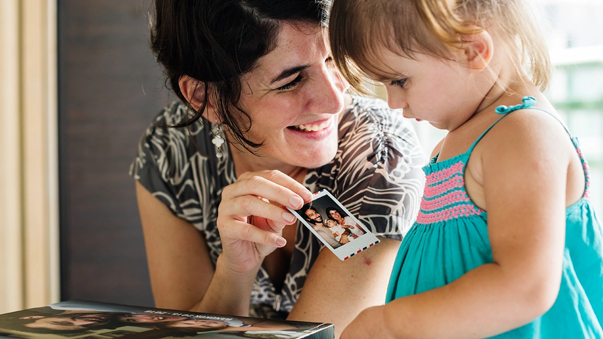 Woman showing a photo to her young daughter.