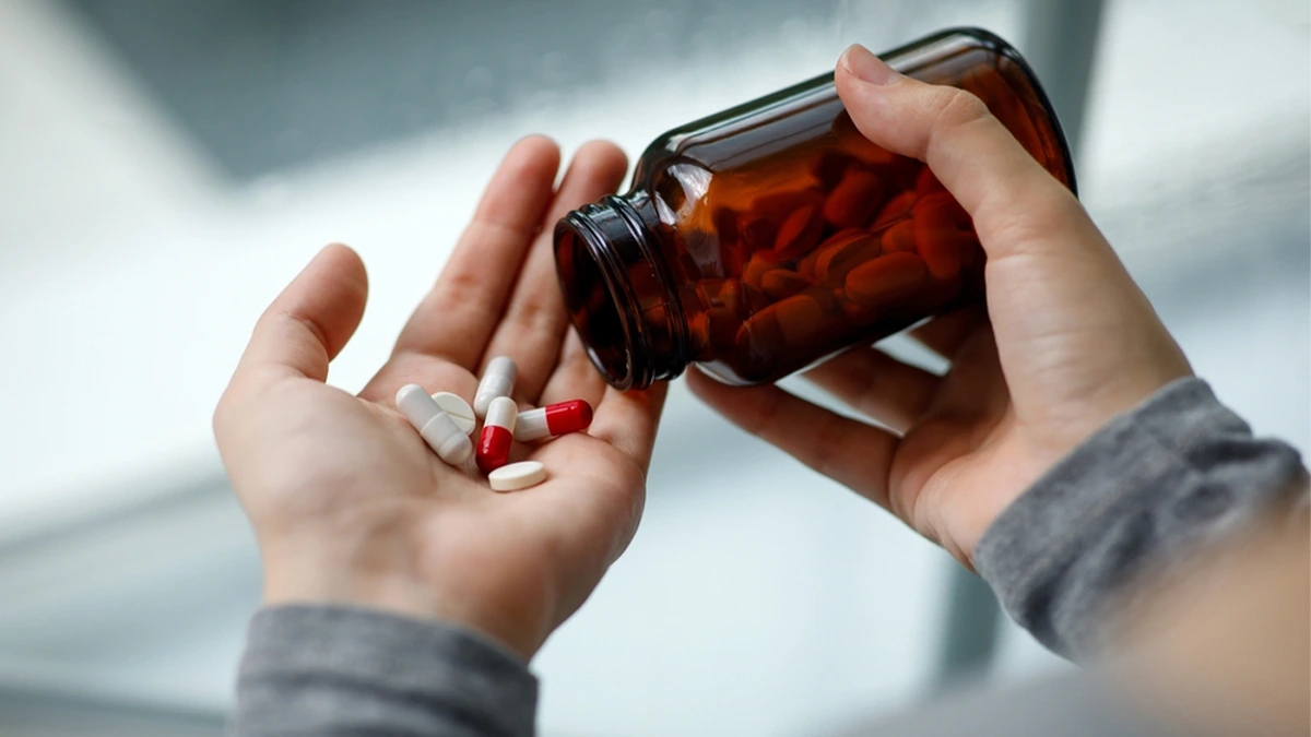 Closeup on hands pouring pills from a pill bottle into the palm of the other hand. There are several risk factors for Suboxone addiction.