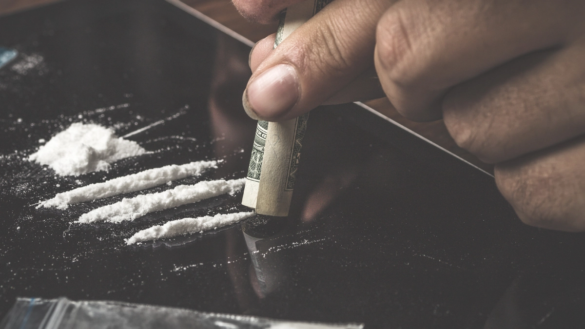 A man snorting powdered ketamine using a paper roll.