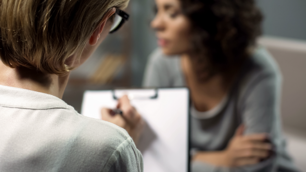 therapist writing notes while listening to a client